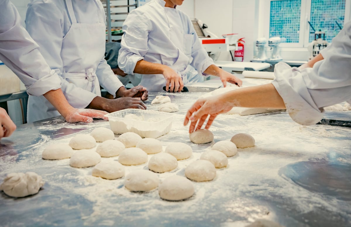 Professional bakery team working with fresh dough in a commercial kitchen, representing the type of food production business our lease solicitors for bakeries advise across England and Wales