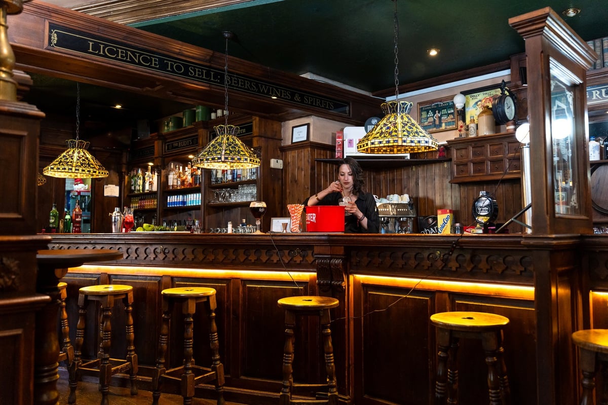 Traditional British pub interior with bartender serving drinks at a classic wooden bar. Specialist lease solicitors for bars and pubs advise on commercial property leases for licensed premises across England and Wales.