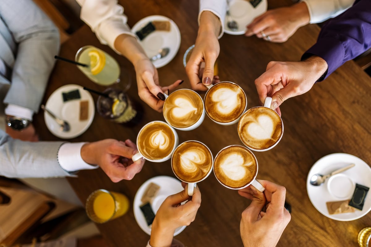 Close-up of friends clinking coffee cups in a cozy cafe